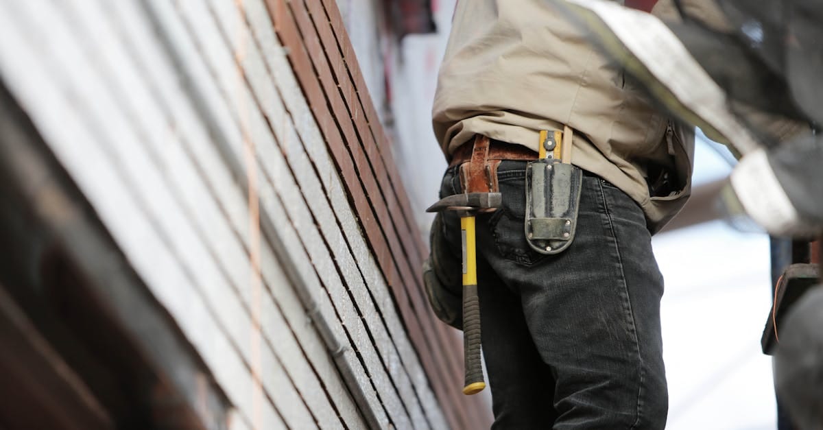 Close-up of a construction worker with hammer and tools, focused on the job.